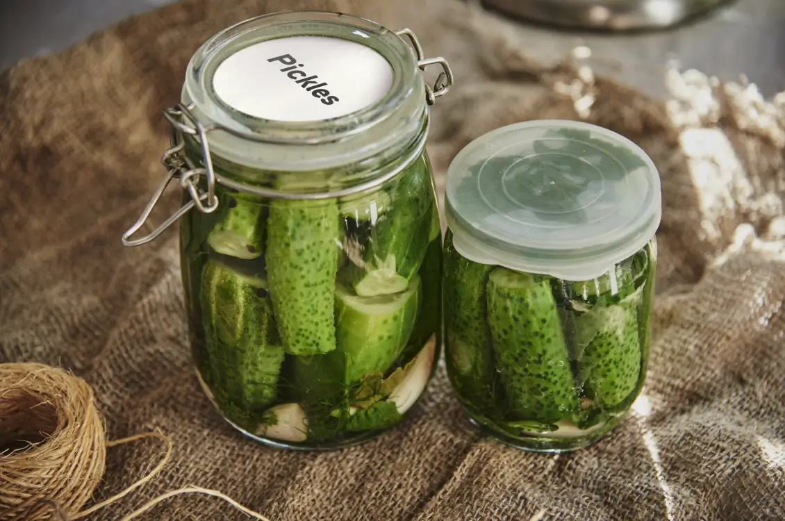 Two pickling jars on a burlap tablecloth.