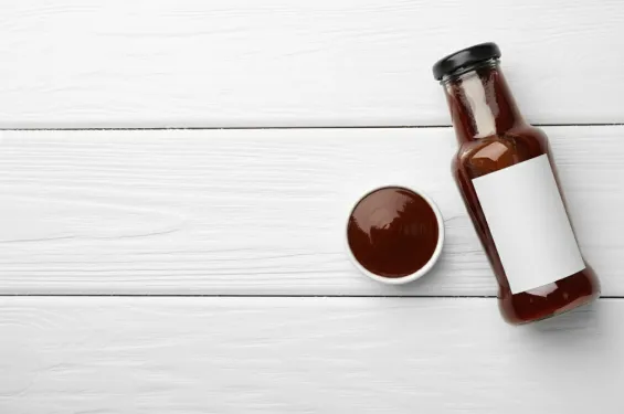 Hand holding a barbecue sauce bottle with blank label