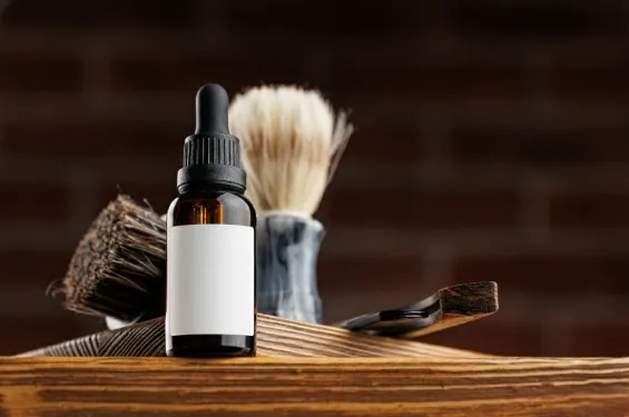 Beard oil bottle with grooming tools on a wooden table