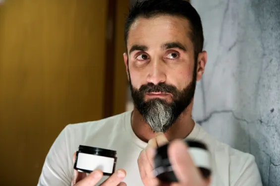 Man applying beard balm with a labeled container